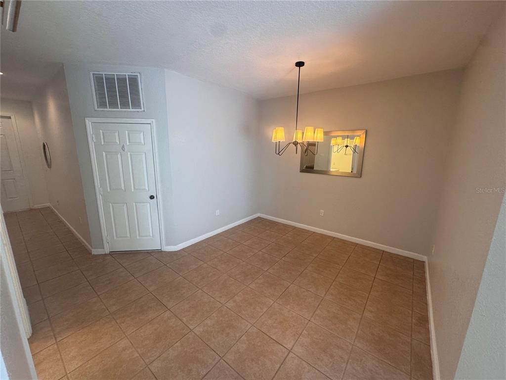 A dining room features tan tile flooring, a chandelier, and a mirror on the wall — 3469 ALLEGRA CIRCLE, ST CLOUD, FL