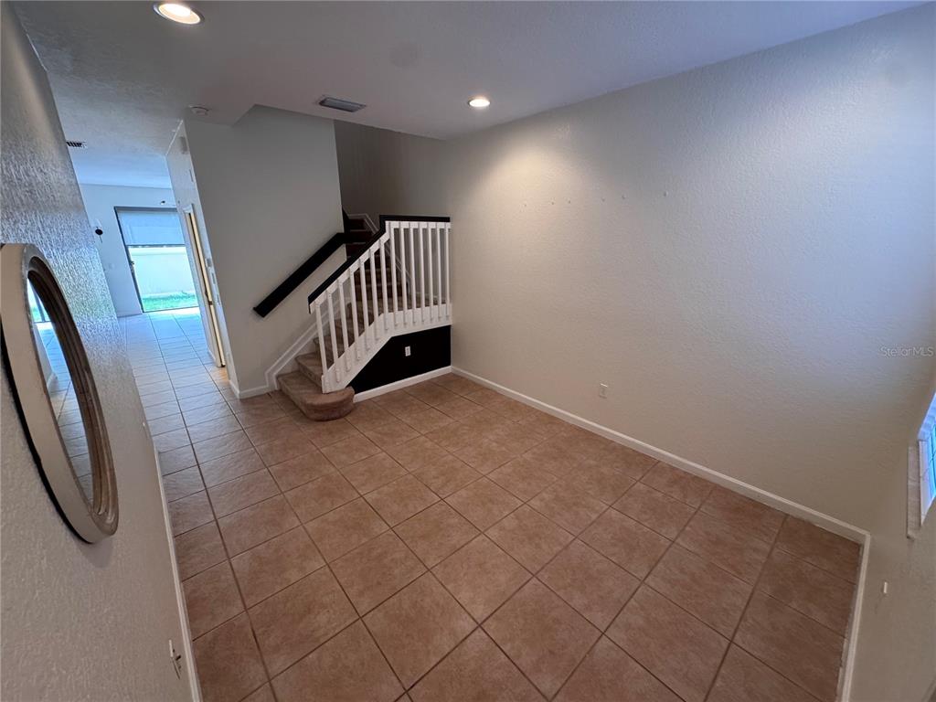 An interior view shows a tiled room with a staircase featuring white railings and carpeted steps — 3469 ALLEGRA CIRCLE, ST CLOUD, FL