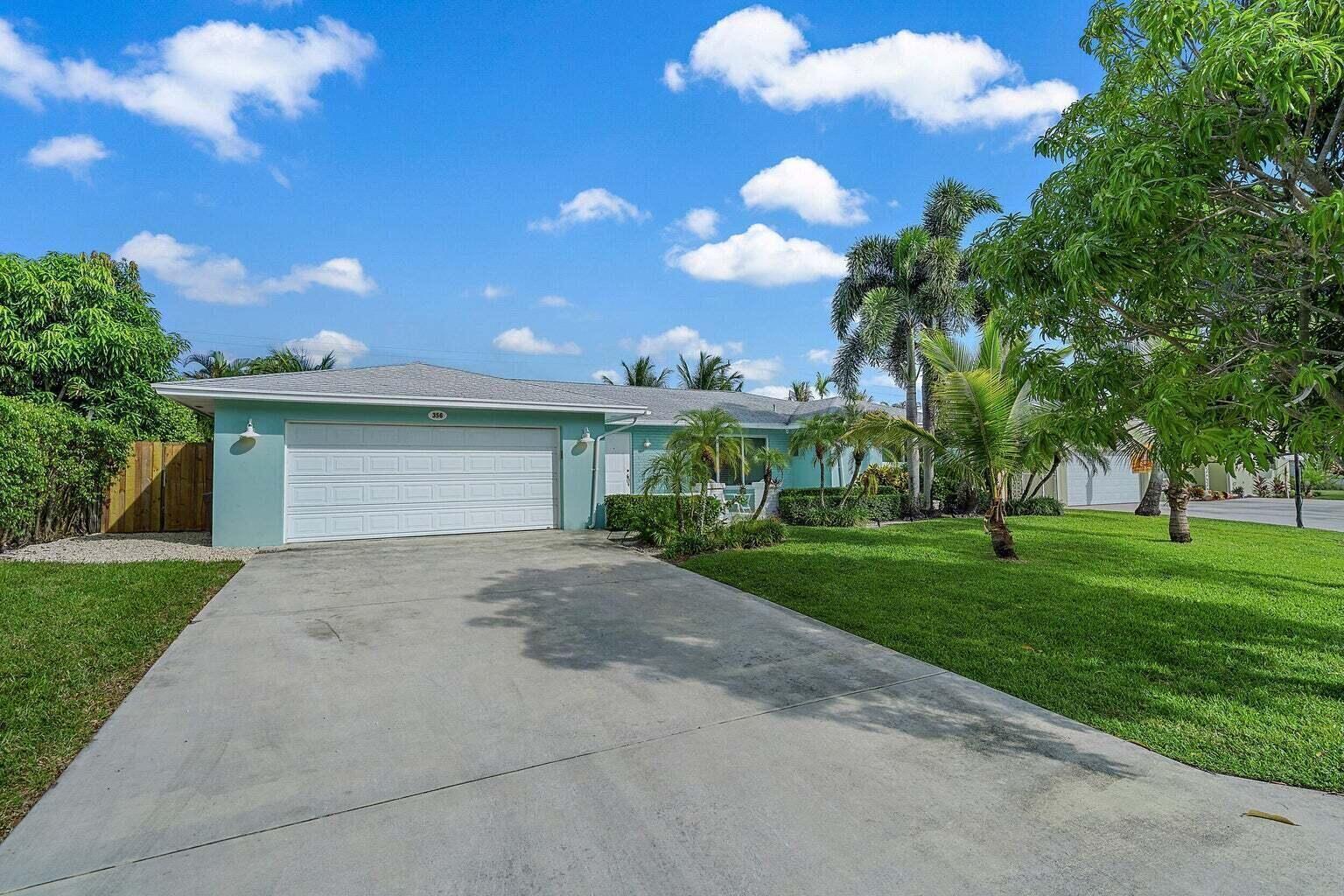 A light blue single-story house with a white garage door and a concrete driveway — 356 Mars Avenue, Tequesta FL 33469, TEQUESTA, FL