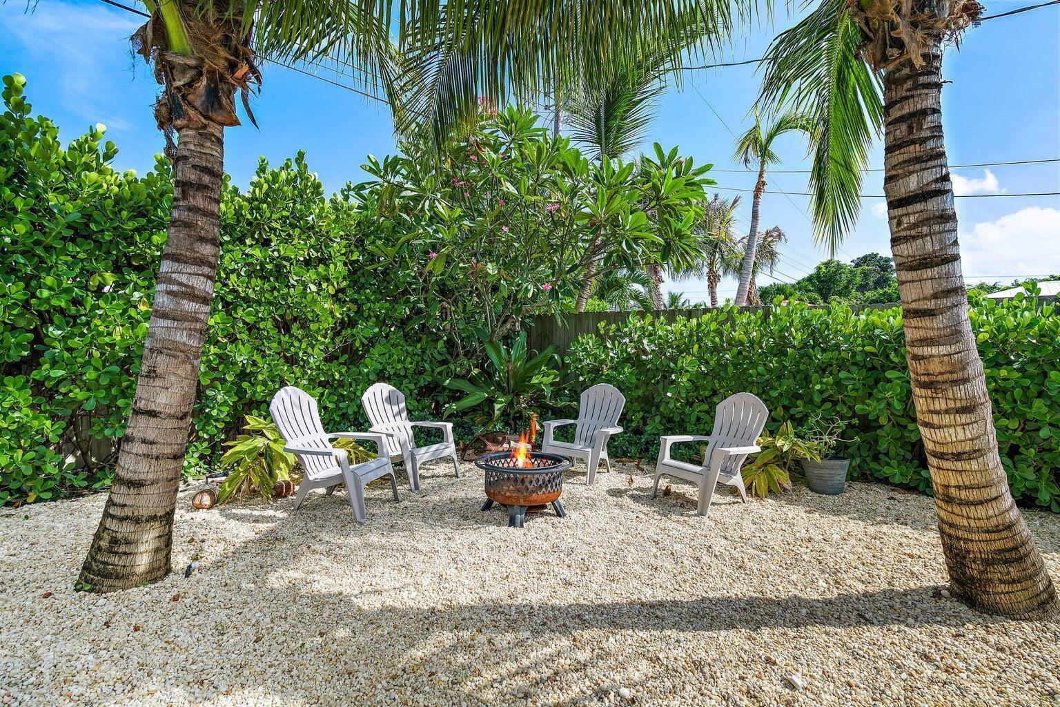 Four Adirondack chairs surround a fire pit on a gravel patio between two palm trees — 356 Mars Avenue, Tequesta FL 33469, TEQUESTA, FL