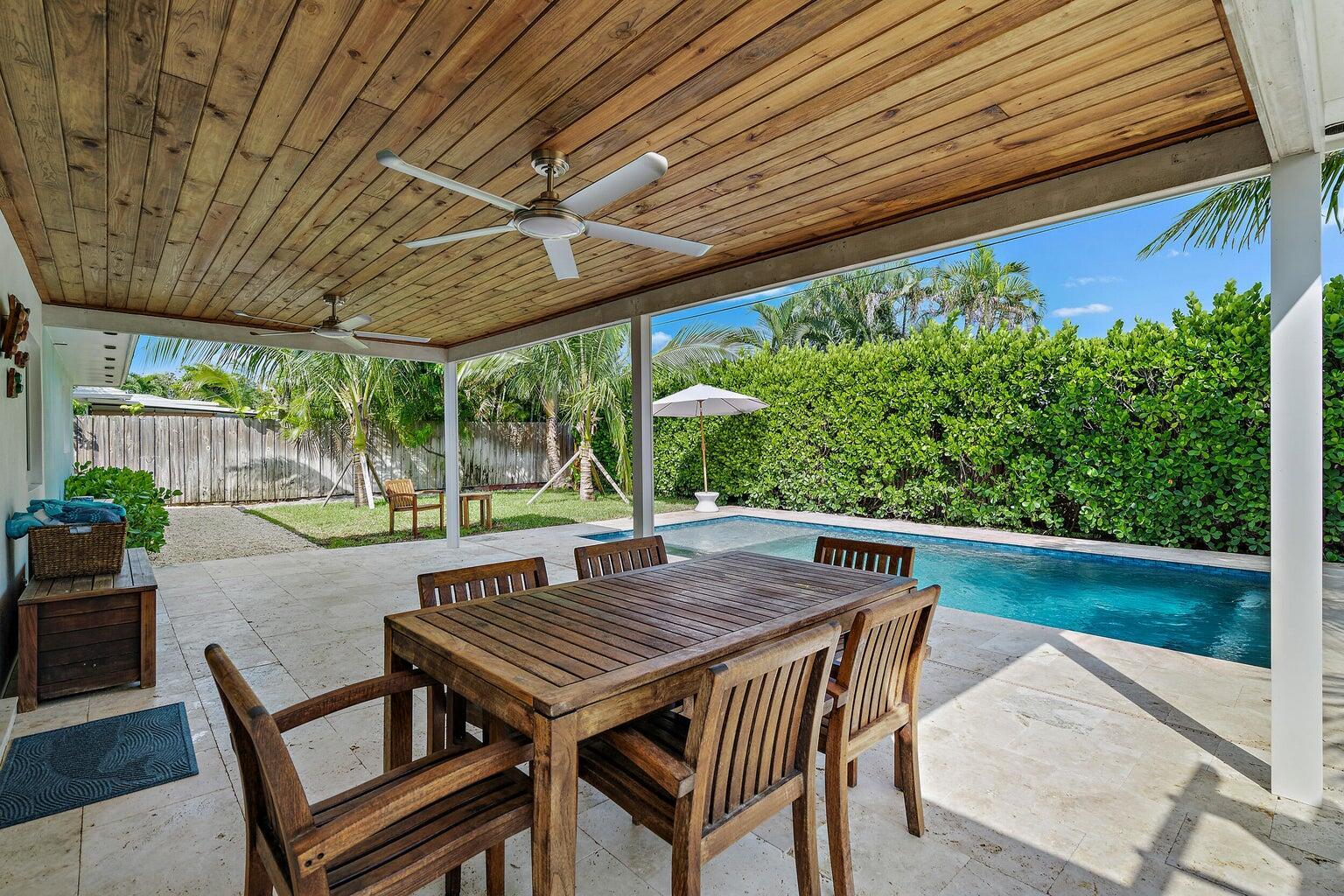 A covered patio with a wooden ceiling, dining set, and pool overlooking a landscaped yard — 356 Mars Avenue, Tequesta FL 33469, TEQUESTA, FL