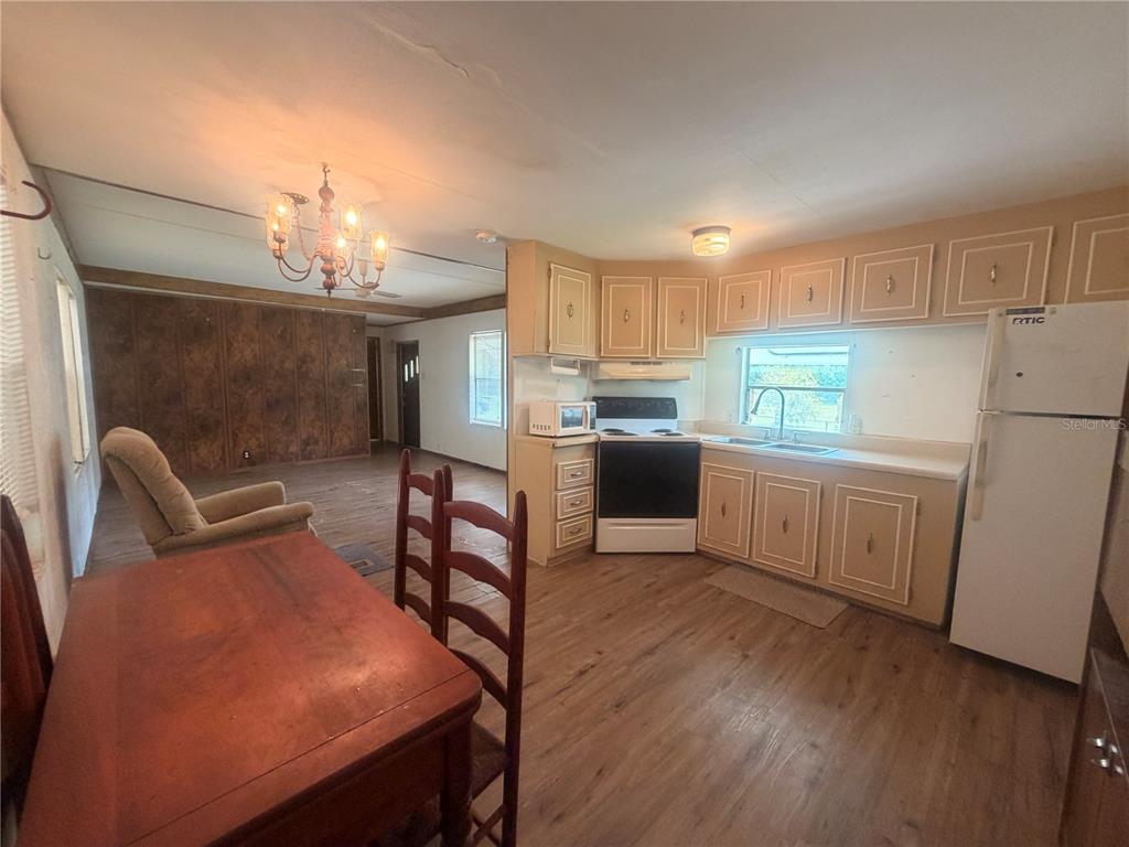 A kitchen with light-colored cabinets and wood-look flooring opens into a dining and living area — 8582 W ADMIRAL BYRD LANE, CRYSTAL RIVER, FL