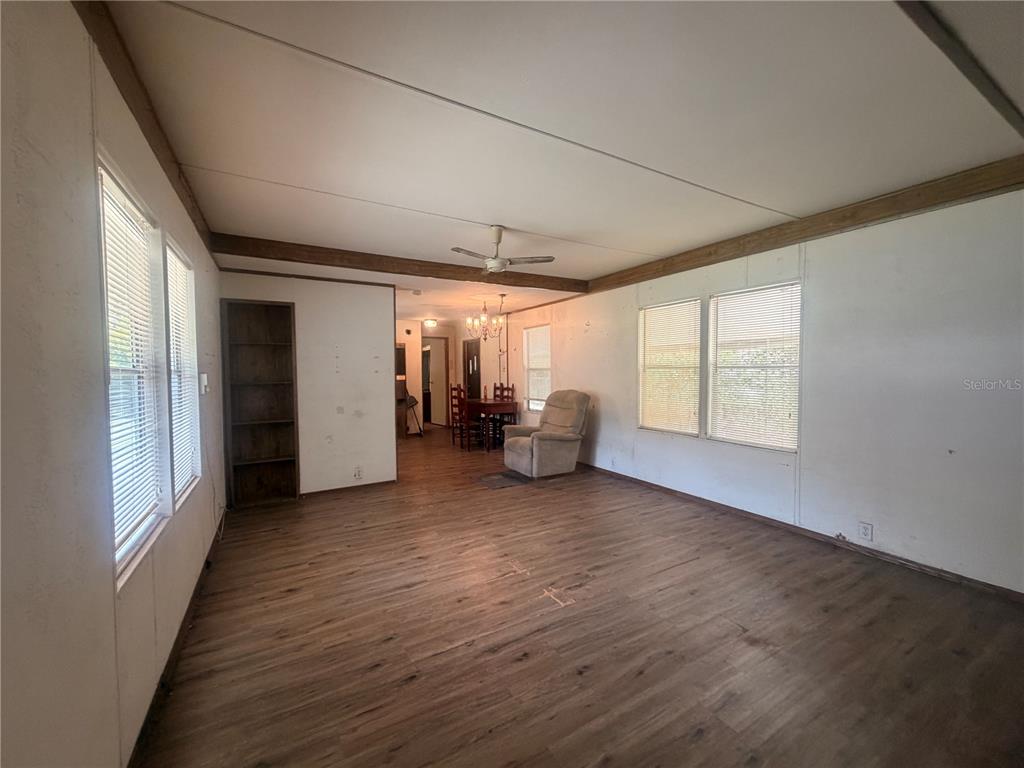 A living room with wood-look flooring, white walls, a ceiling fan, and a dining area — 8582 W ADMIRAL BYRD LANE, CRYSTAL RIVER, FL