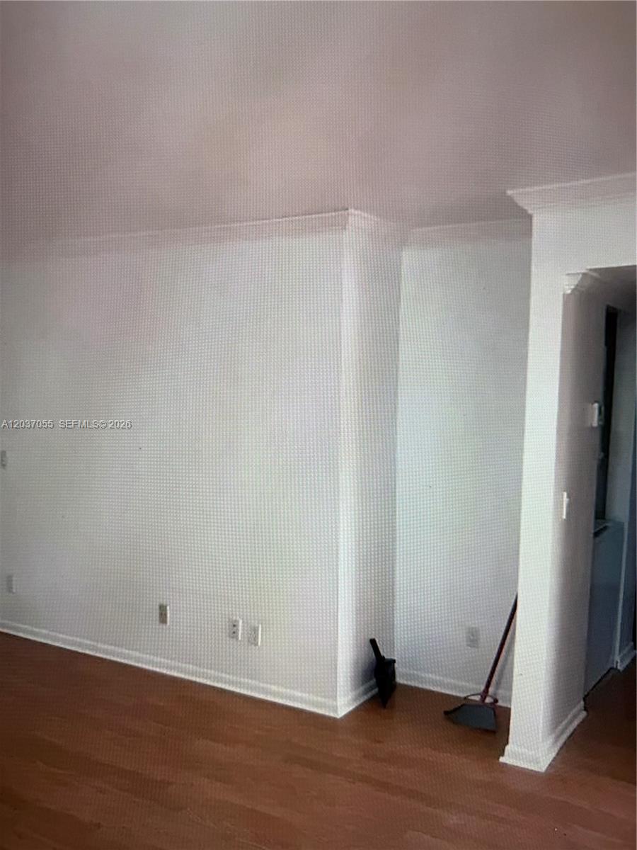 An interior view shows a white wall with crown molding and wood-look flooring — 17000 NW 67th Ave # 445, Hialeah FL 33015, HIALEAH, FL