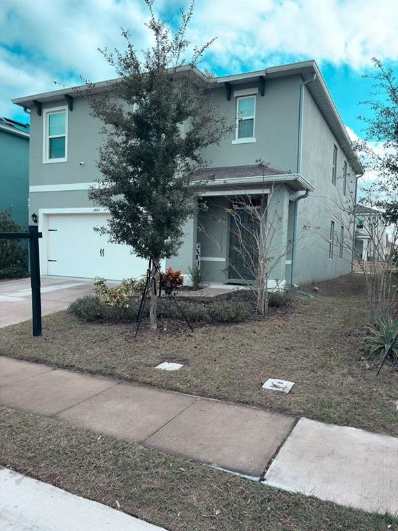 A two-story light gray house with a white garage door and a small front yard — 1447 BERRY LANE, DAVENPORT, FL
