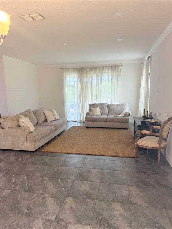 A living room features gray tile flooring, two beige sofas, and a large area rug — 14305 FISSORE BOULEVARD, WIMAUMA, FL