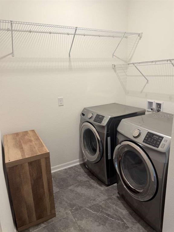 A laundry room features grey tile flooring, wire shelving, and a side-by-side washer and dryer — 14305 FISSORE BOULEVARD, WIMAUMA, FL