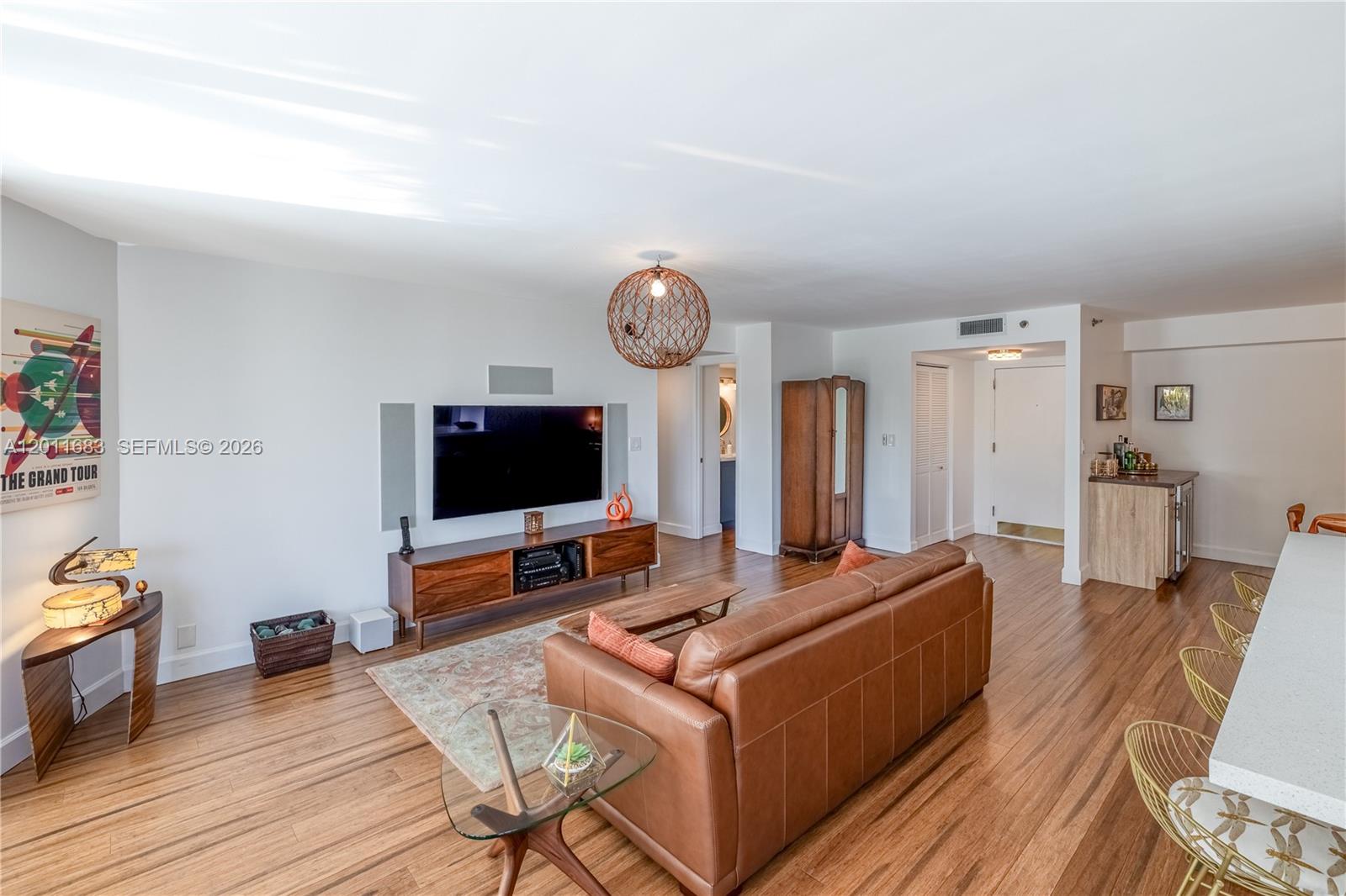 A living room features a leather sofa, wood flooring, a television, and a bar area — 4000 Towerside Ter # 308, Miami FL 33138, MIAMI, FL