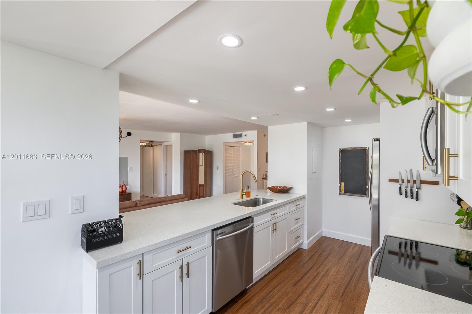 A modern kitchen features white cabinets, stainless steel appliances, and a long quartz countertop — 4000 Towerside Ter # 308, Miami FL 33138, MIAMI, FL