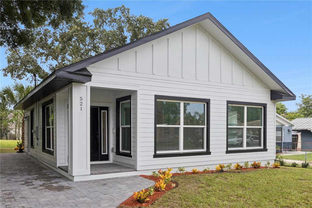 A white house with black trim and a paved walkway sits on a grassy lot — 521 W HERRIOTT AVENUE, OAKLAND, FL