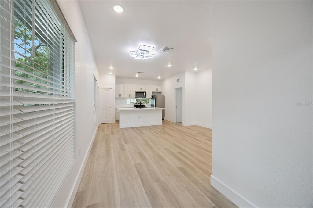 A bright, open-concept kitchen and living area featuring white cabinetry, an island, and wood flooring — 521 W HERRIOTT AVENUE, OAKLAND, FL