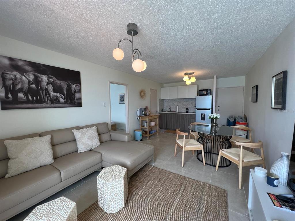 A living room and kitchen area feature a sectional sofa, dining table, and tile flooring — Tower 1 ISLETA MARINA UNIT 4C, FAJARDO, PR