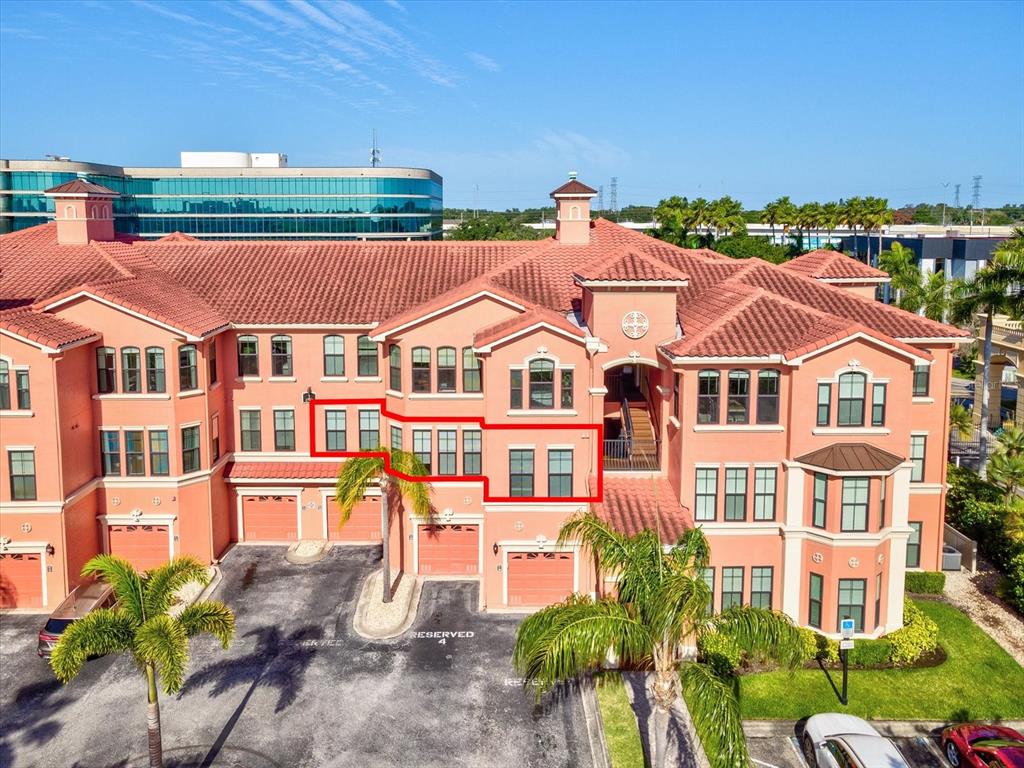 An exterior view of a multi-story peach-colored building with a red tile roof — 2705 VIA MURANO UNIT 123, CLEARWATER, FL
