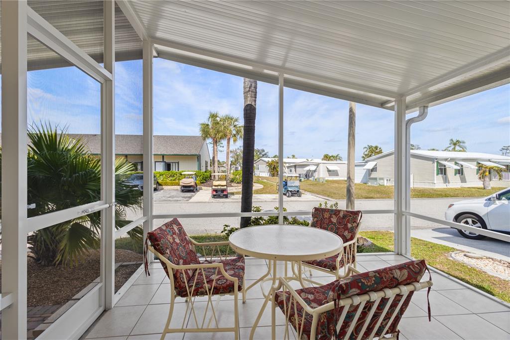 A screened-in patio features a round table with three chairs and views of a neighborhood — 2100 KINGS HIGHWAY UNIT 870, PORT CHARLOTTE, FL