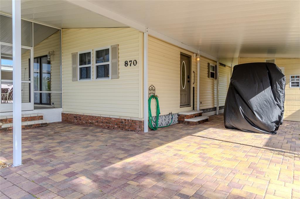 A paved carport leads to the entrance of a house with light yellow siding — 2100 KINGS HIGHWAY UNIT 870, PORT CHARLOTTE, FL