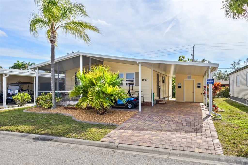 A single-story manufactured home features a paved driveway, a carport, and a screened-in porch — 2100 KINGS HIGHWAY UNIT 870, PORT CHARLOTTE, FL