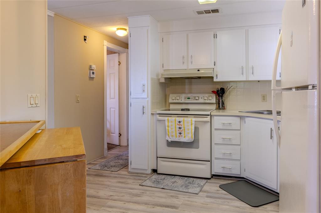 A kitchen features white cabinets, a white stove, and light wood-look flooring — 2100 KINGS HIGHWAY UNIT 870, PORT CHARLOTTE, FL