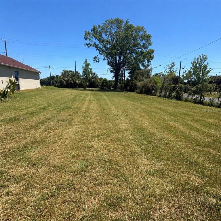 A large, mowed grassy lot sits next to a house under a clear blue sky — 2501 N 55TH STREET UNIT 1, TAMPA, FL