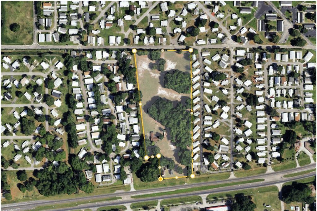 An aerial view shows a rectangular plot of land outlined in yellow within a neighborhood — 4011 S ORANGE BLOSSOM TRAIL, KISSIMMEE, FL