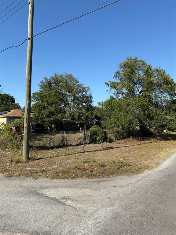 A vacant, grassy residential lot features a utility pole and mature trees under a clear sky — 3601 N GARRISON STREET, TAMPA, FL