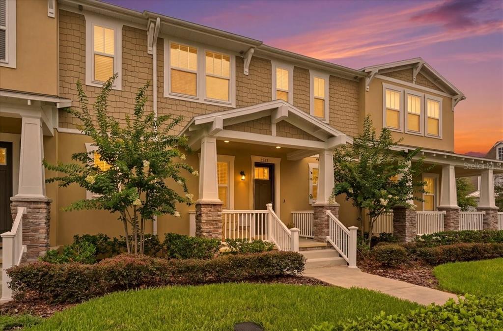 A two-story townhouse exterior with tan siding, stone accents, and a covered front porch — 2253 CELEBRATION BOULEVARD, CELEBRATION, FL