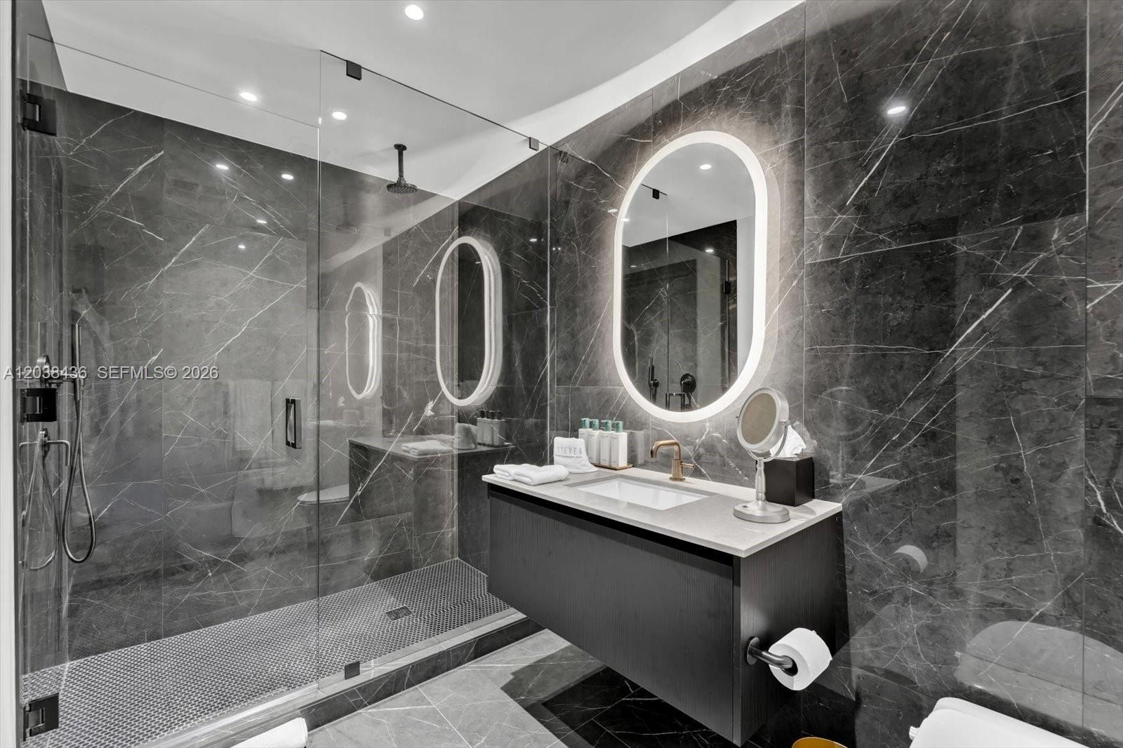 A modern bathroom features dark marble walls, a floating vanity, and a glass-enclosed shower — 20 NE 11th St # 3105, Miami FL 33132, MIAMI, FL
