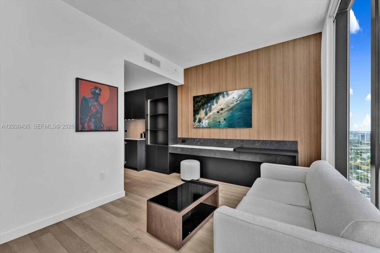 A modern living room features light wood floors, a white sofa, and a wood-paneled wall — 20 NE 11th St # 3105, Miami FL 33132, MIAMI, FL