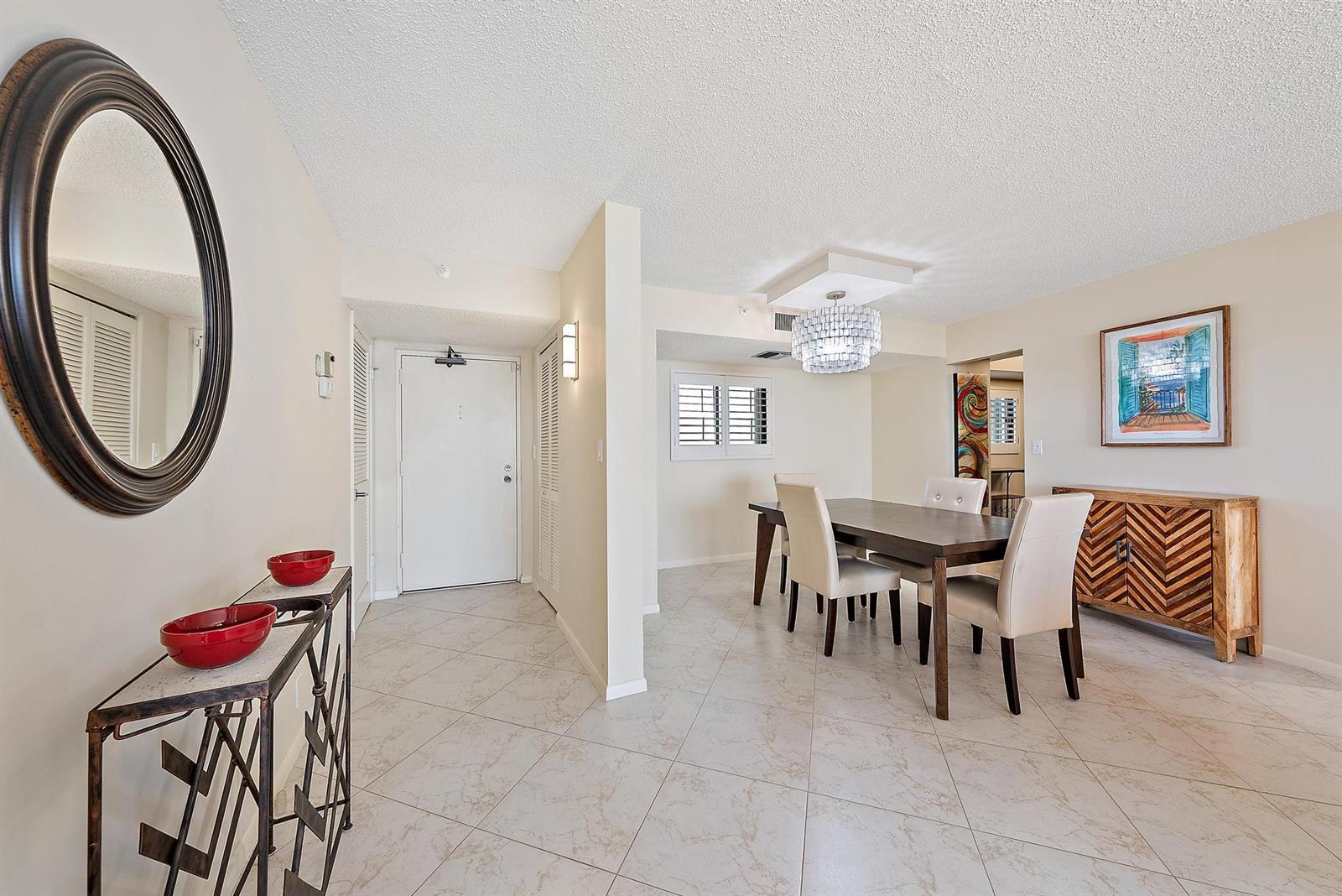 A dining room with a chandelier, wooden table, and tiled floors near an entryway — 400 Ocean Trail Way # 707, Jupiter FL 33477, JUPITER, FL