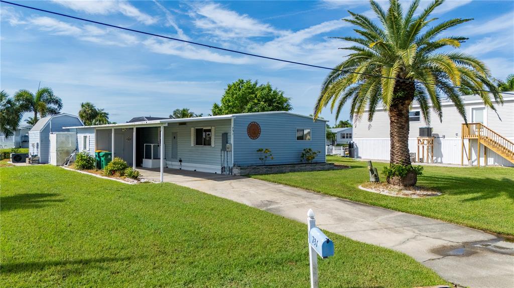A light blue mobile home with a carport and a large palm tree in front — 731 TANGERINE COURT, PUNTA GORDA, FL