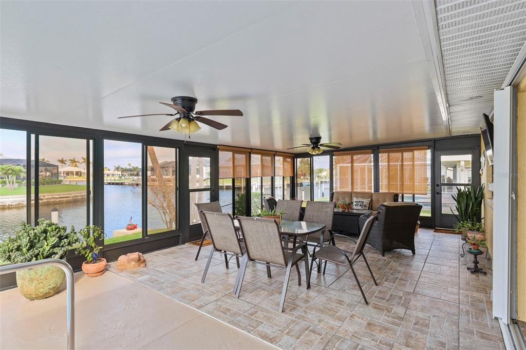 A screened-in patio features tile flooring, a dining set, wicker furniture, and waterfront views — 611 BAL HARBOR BOULEVARD, PUNTA GORDA, FL
