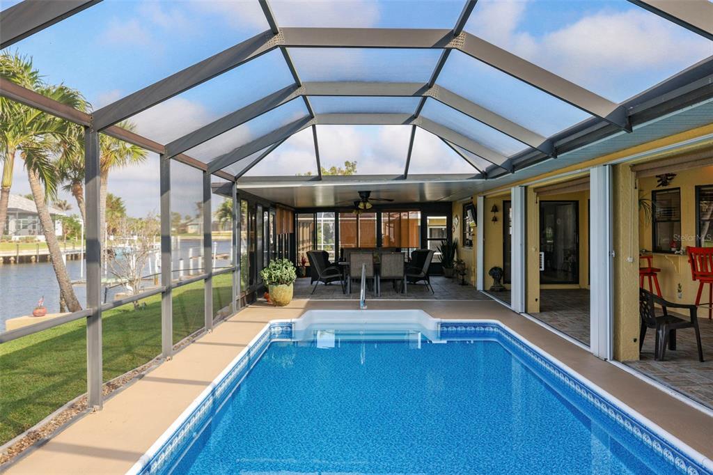 A screened-in lanai features a rectangular swimming pool, a dining area, and waterfront views — 611 BAL HARBOR BOULEVARD, PUNTA GORDA, FL