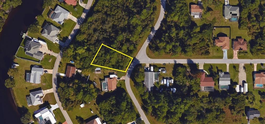 An aerial view shows a vacant, trapezoidal lot outlined in yellow situated between two residential streets — 468 KELLSTADT STREET NW, PORT CHARLOTTE, FL