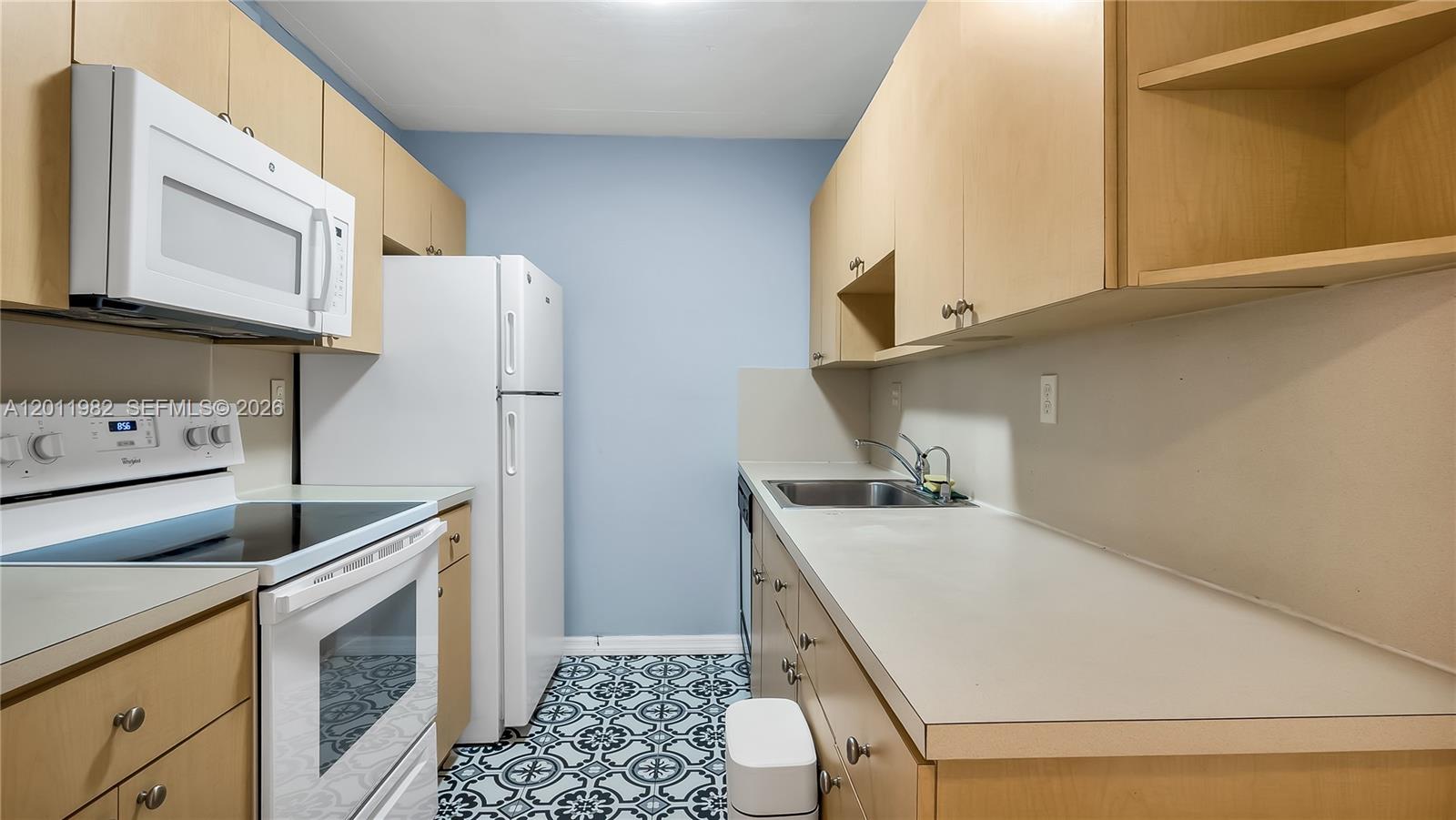 A galley kitchen features light wood cabinets, white appliances, and patterned tile flooring — 7231 Miami Lakes Dr # C5, Miami Lakes FL 33014, MIAMI LAKES, FL
