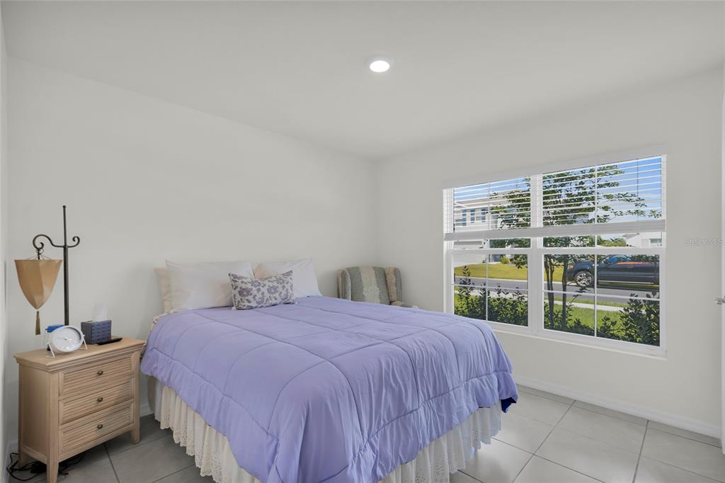 A bedroom with white walls, tile flooring, a purple bedspread, and a large window — 11446 SE 72ND AVENUE, BELLEVIEW, FL