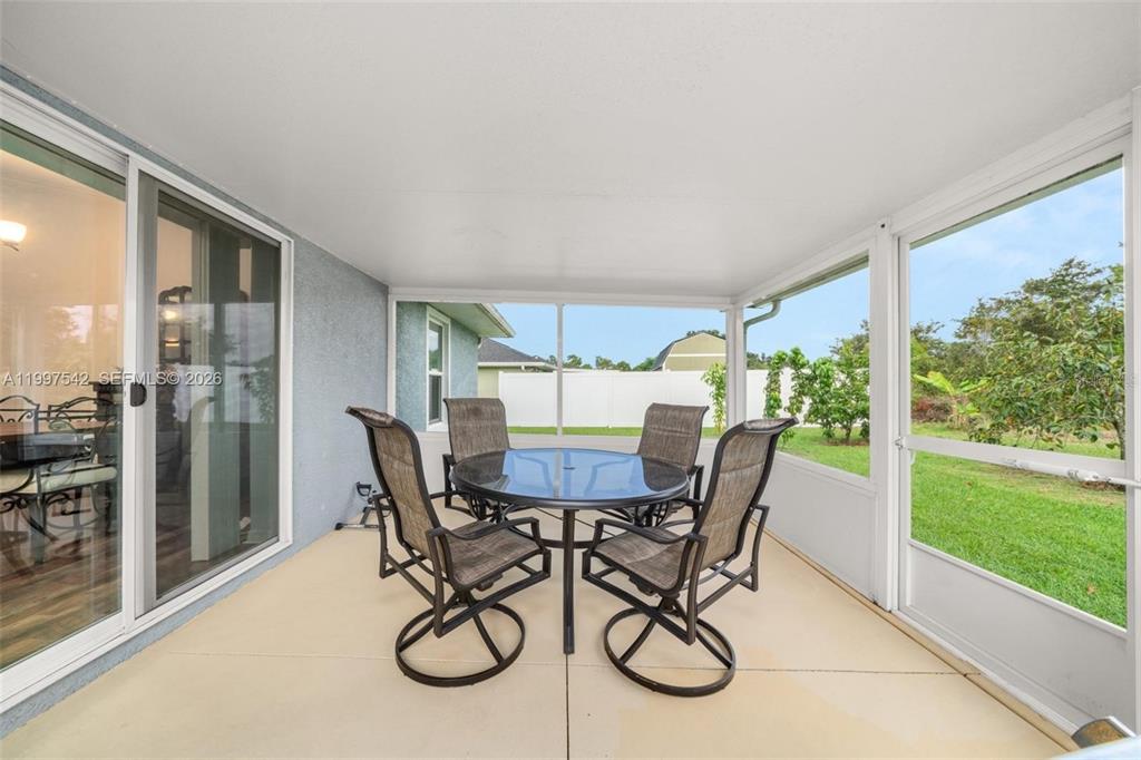 A screened-in patio features a glass-topped dining table with four chairs and sliding glass doors — 112 NE BIMINI STREET NE, LAKE PLACID, FL