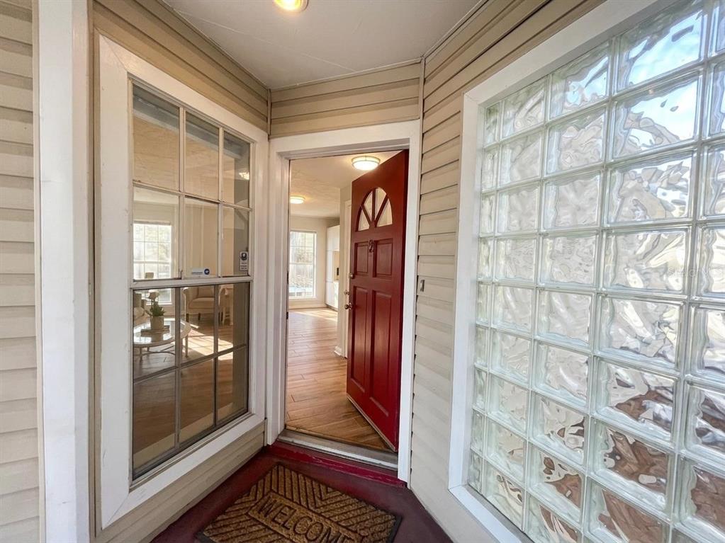 A red front door opens into a home interior, flanked by a window and glass blocks — 508 S GLEN AVENUE UNIT 2, TAMPA, FL