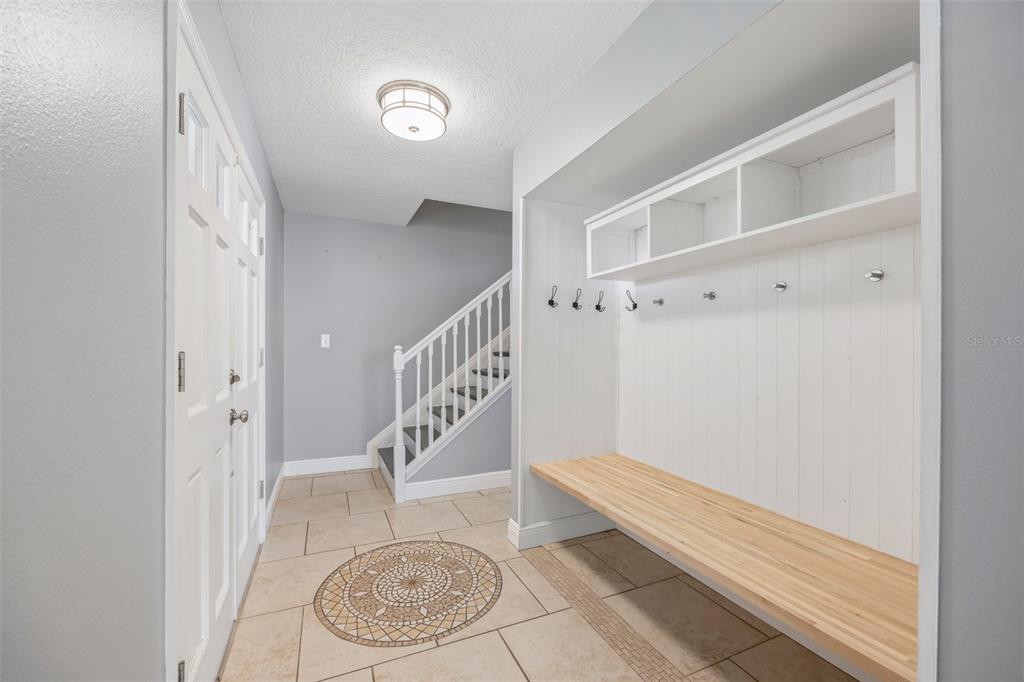 An entryway features a built-in mudroom bench, coat hooks, overhead storage, and a staircase — 204 YORK DRIVE, COCOA, FL