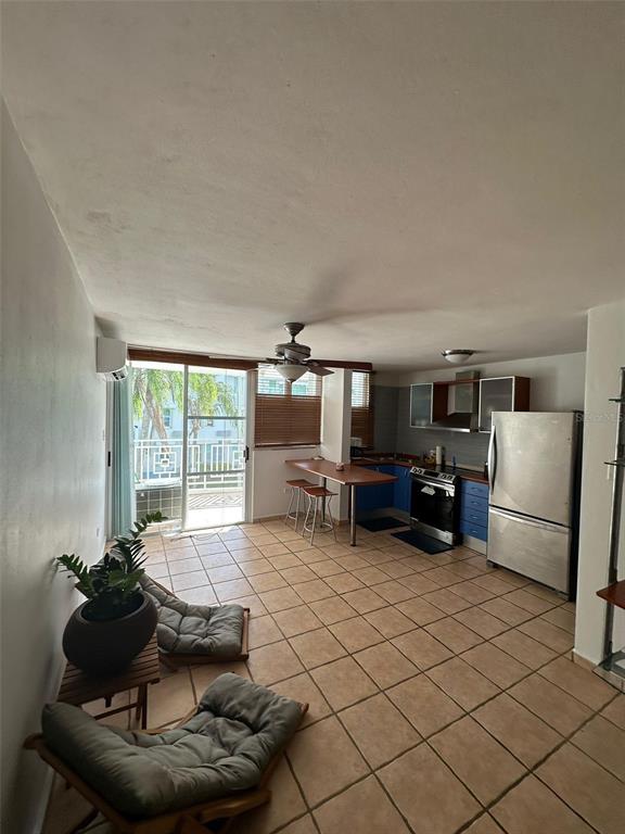 An open-concept kitchen and living area features tile flooring, a ceiling fan, and balcony access — 1502 OCEAN POINT UNIT 1, LOIZA, PR