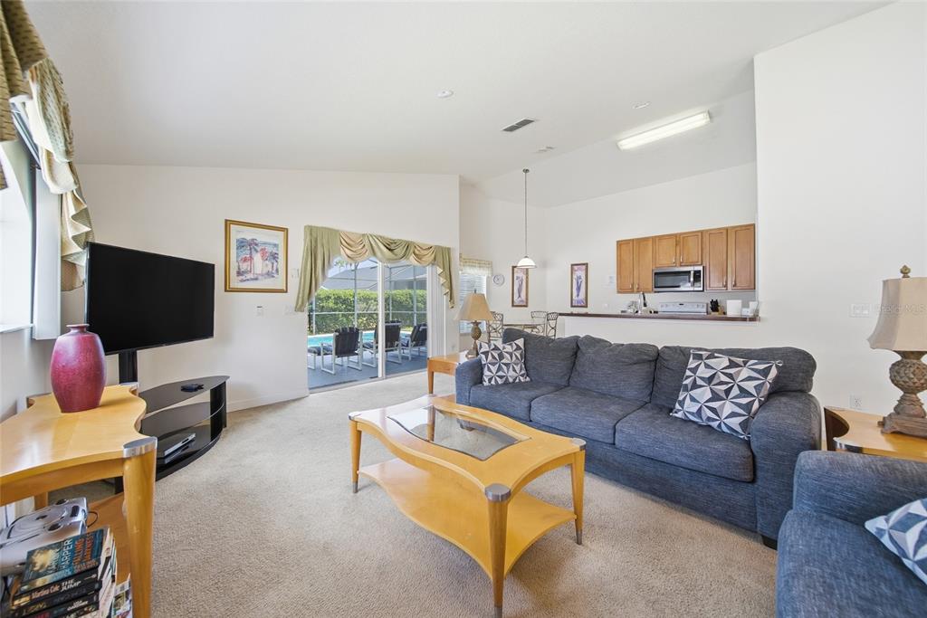 A living room features a grey sofa, a wooden coffee table, and a sliding door — 723 OLD BRIDGE CIRCLE, DAVENPORT, FL
