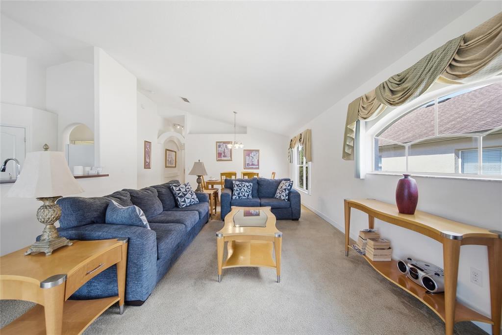 A living room features blue sofas, light wood furniture, and a large arched window — 723 OLD BRIDGE CIRCLE, DAVENPORT, FL
