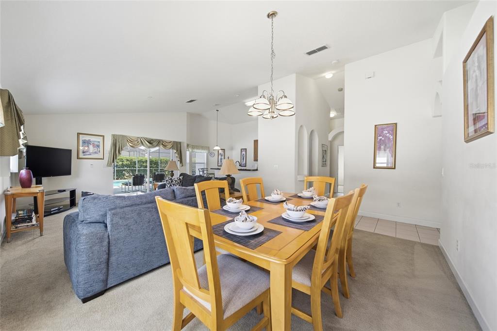 A dining area with a wooden table and chairs sits adjacent to a living room — 723 OLD BRIDGE CIRCLE, DAVENPORT, FL