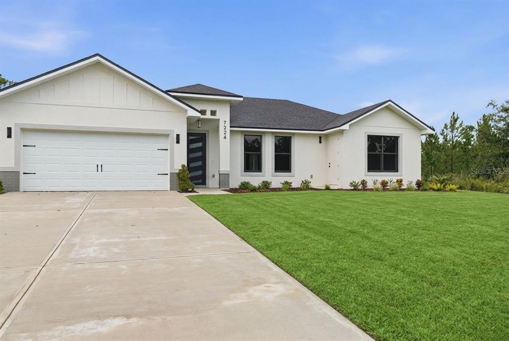 A single-story house with a white exterior, dark roof, and a concrete driveway — 7224 GRANADA BOULEVARD, SEBRING, FL