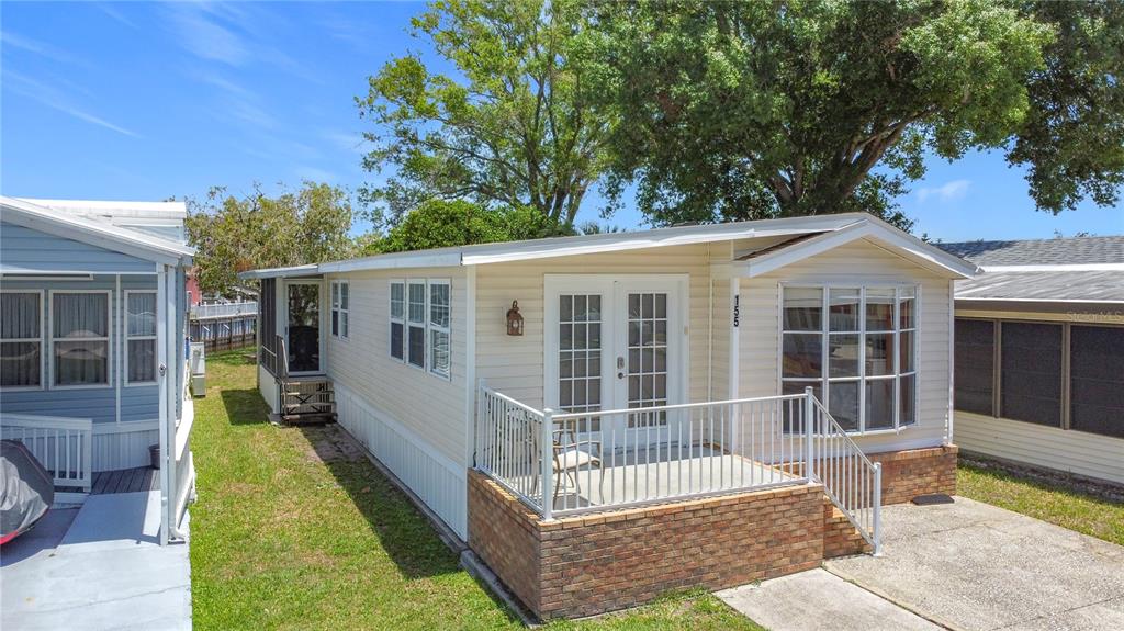 A light-colored mobile home features a brick-based front porch, French doors, and a bay window — 9000 US HIGHWAY 192 UNIT 155, CLERMONT, FL