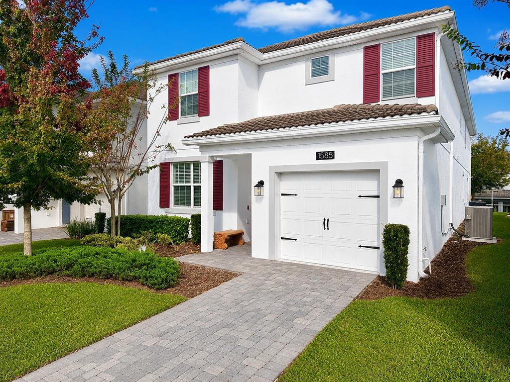A two-story white house with red shutters, a single-car garage, and a paved walkway — 1585 FLANGE DRIVE, DAVENPORT, FL