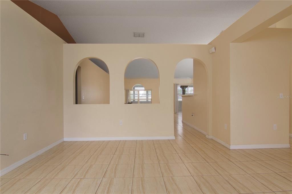 An interior room features light-colored tile flooring, beige walls, and three arched wall openings — 107 FLATFISH COURT, POINCIANA, FL