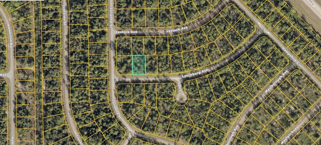 This is an aerial map showing a highlighted vacant residential lot in a wooded neighborhood — 1132212720 LYNCHBURG AVENUE, NORTH PORT, FL