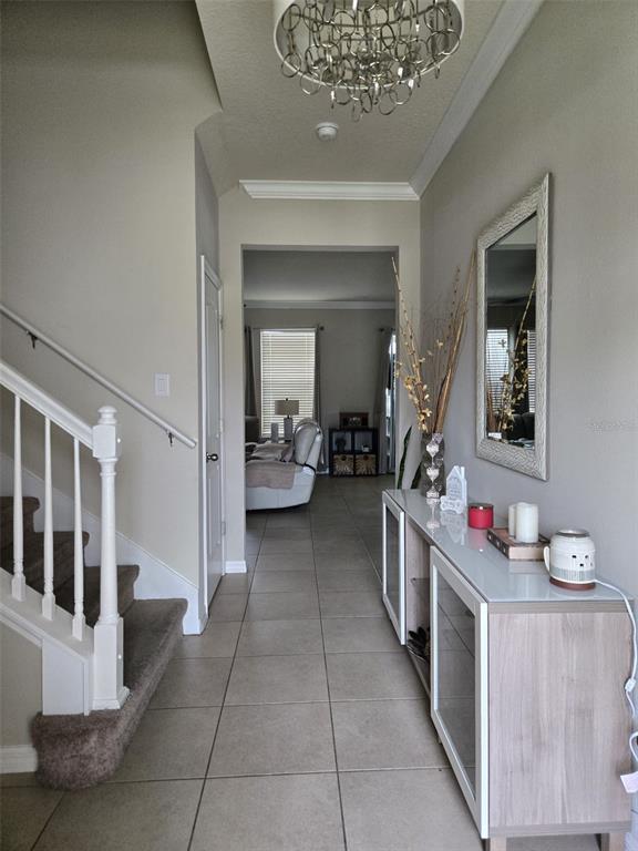 A tiled entryway features a staircase, a console table with a mirror, and a chandelier — 1517 SOFTSHELL STREET, ST CLOUD, FL