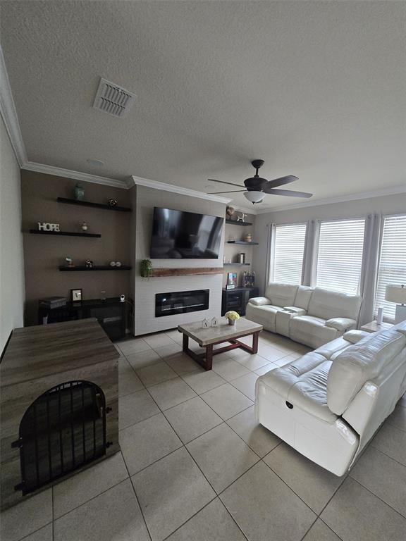 A living room features a fireplace with a mounted television, floating shelves, and white sofas — 1517 SOFTSHELL STREET, ST CLOUD, FL