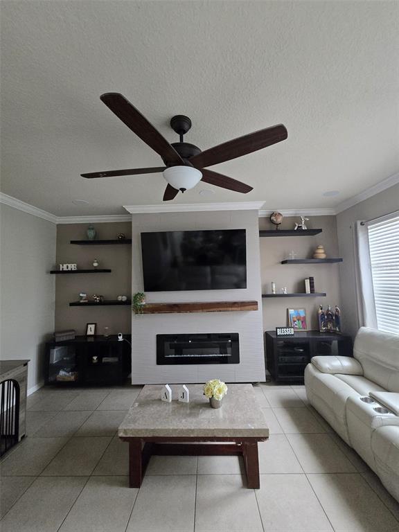 A living room features a fireplace with a mounted television, floating shelves, and tile flooring — 1517 SOFTSHELL STREET, ST CLOUD, FL