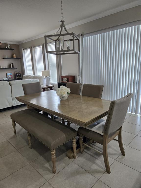 A dining room features a wooden table, a bench, and chairs beneath a metal pendant light — 1517 SOFTSHELL STREET, ST CLOUD, FL